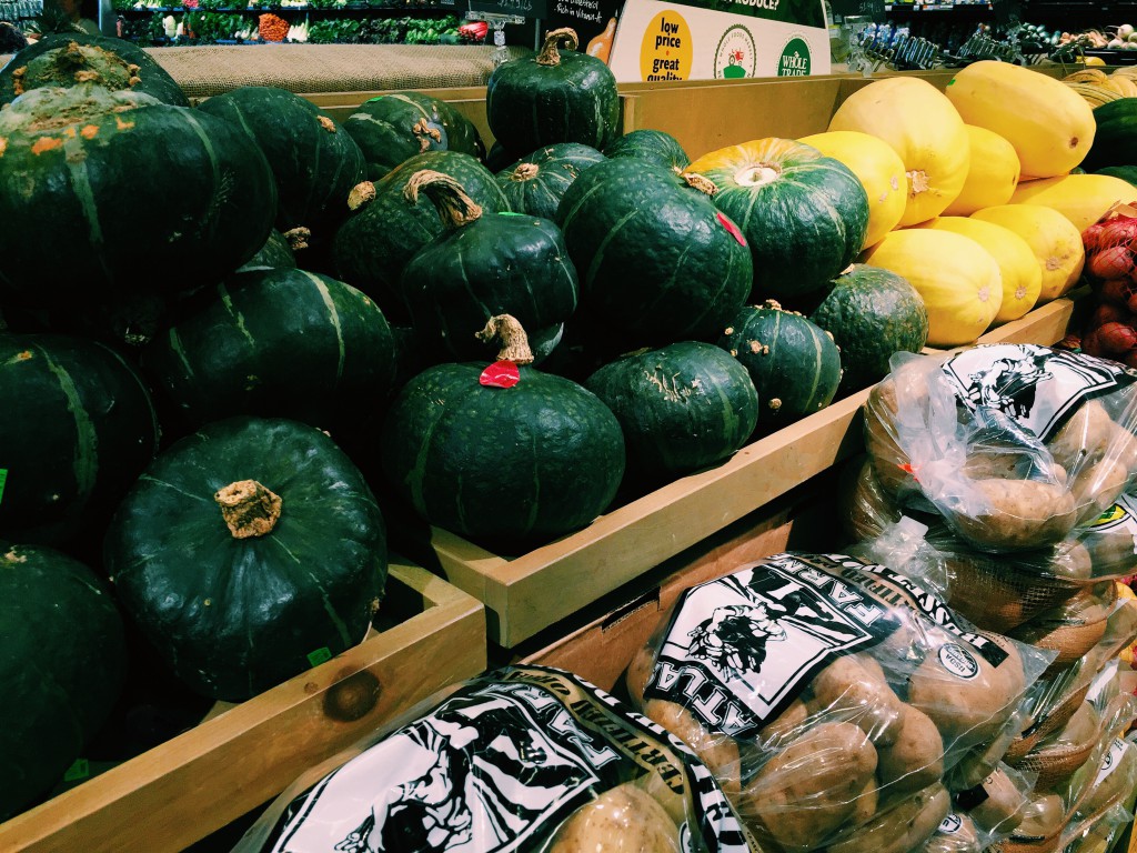 Green and yellow squash above bags of potatoes