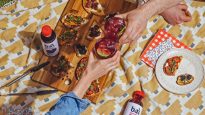 Two people cheersing over Memorial Day snacks and Bai Brasilia Blueberry