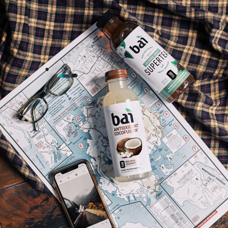 Bai Molokai Coconut and Bai Supertea on a map with glasses and a phone