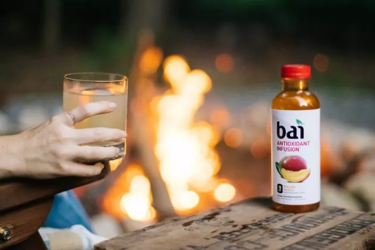 Smokey campfire cocktail by a campfire with Bai Malawi Mango